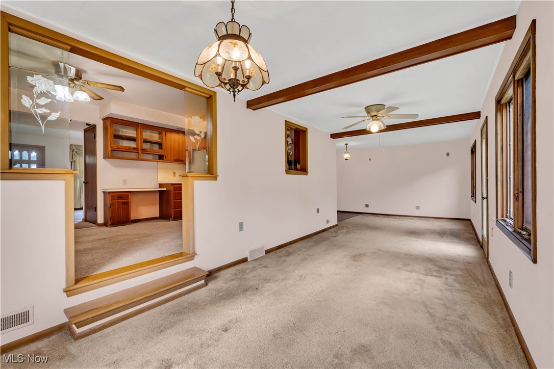 38450 Otten Road North Ridgeville, OH 44039 - Photo 25 of 45 Unfurnished living room with a ceiling fan, beam ceiling, carpet flooring, and a chandelier
