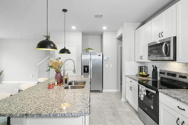 a kitchen with stainless steel appliances granite countertop a sink a stove and a wooden floors