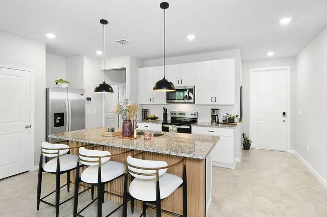 a kitchen with stainless steel appliances kitchen island granite countertop a table chairs and a refrigerator