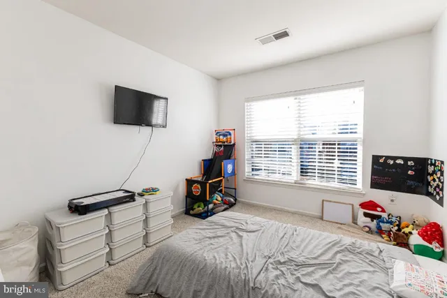 a bedroom with a bed a flat screen tv and a window