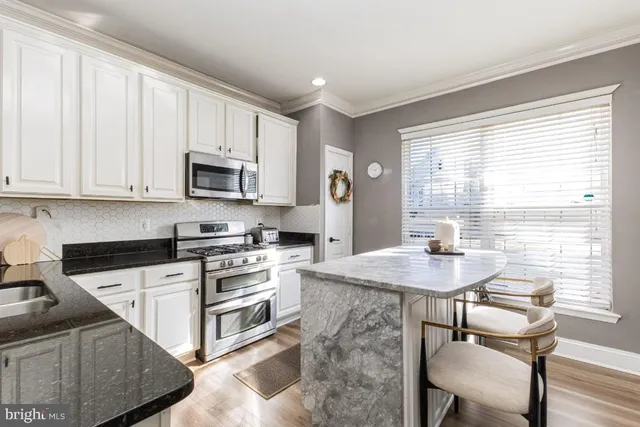a kitchen with kitchen island granite countertop a sink white cabinets and wooden floor
