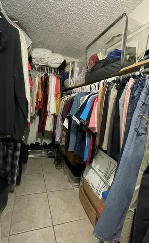 a view of walk in closet with clothes and shoes