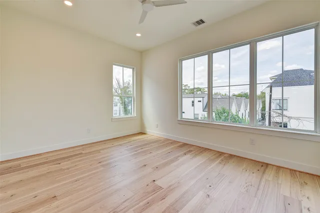 an empty room with wooden floor and windows