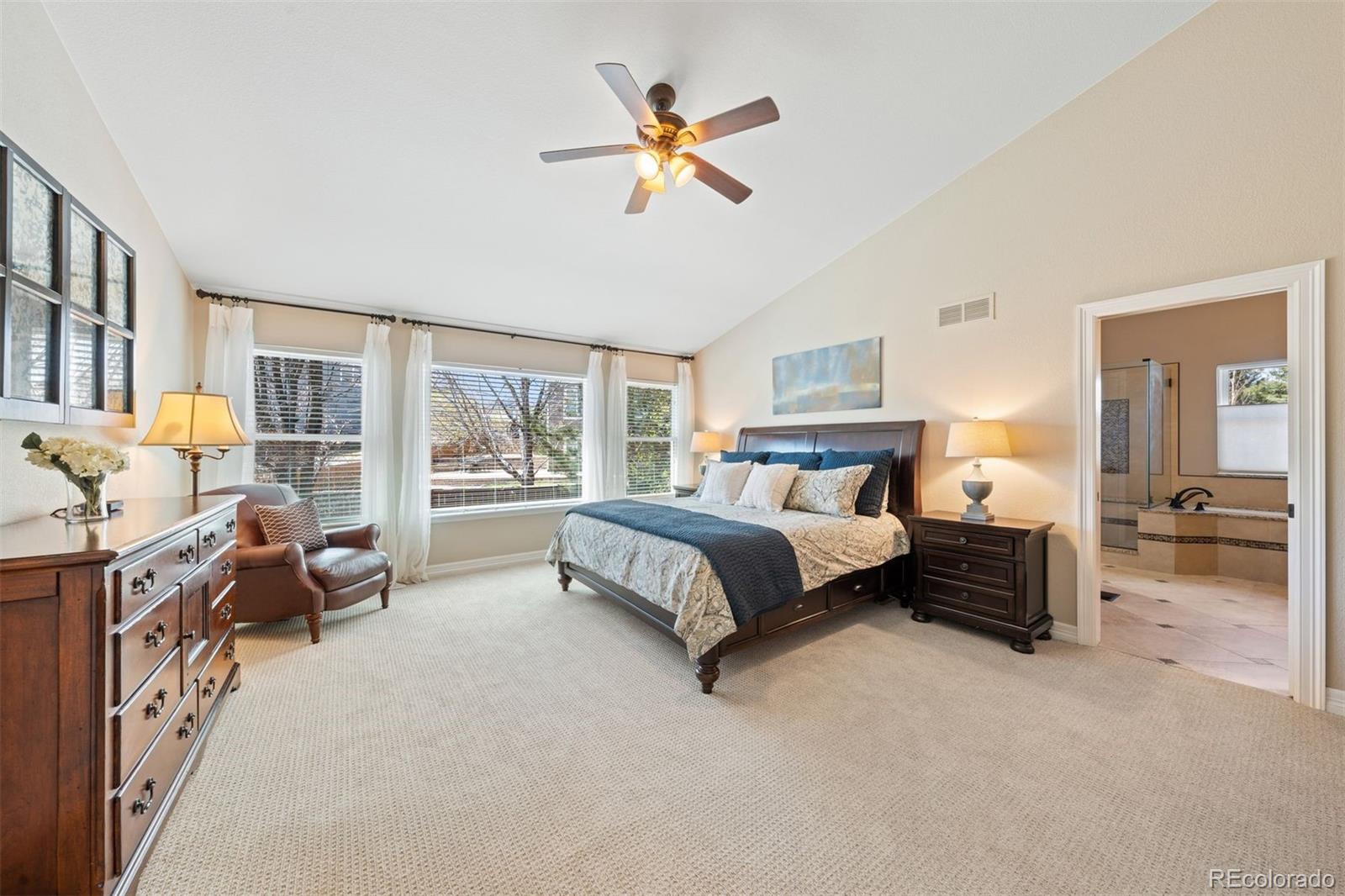 10289 South Dan Court Highlands Ranch, CO 80130 - Photo 16 of 36 a spacious bedroom with a large bed and a chandelier