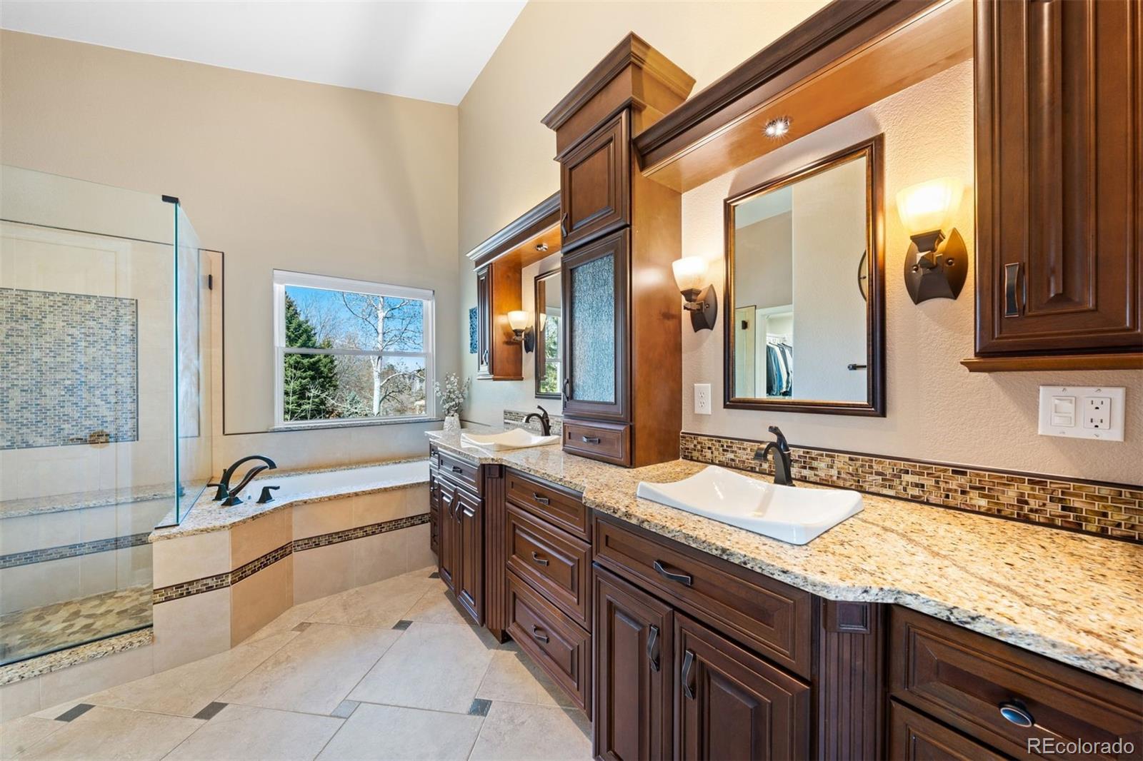 10289 South Dan Court Highlands Ranch, CO 80130 - Photo 18 of 36 a spacious bathroom with a granite countertop tub sink and mirror