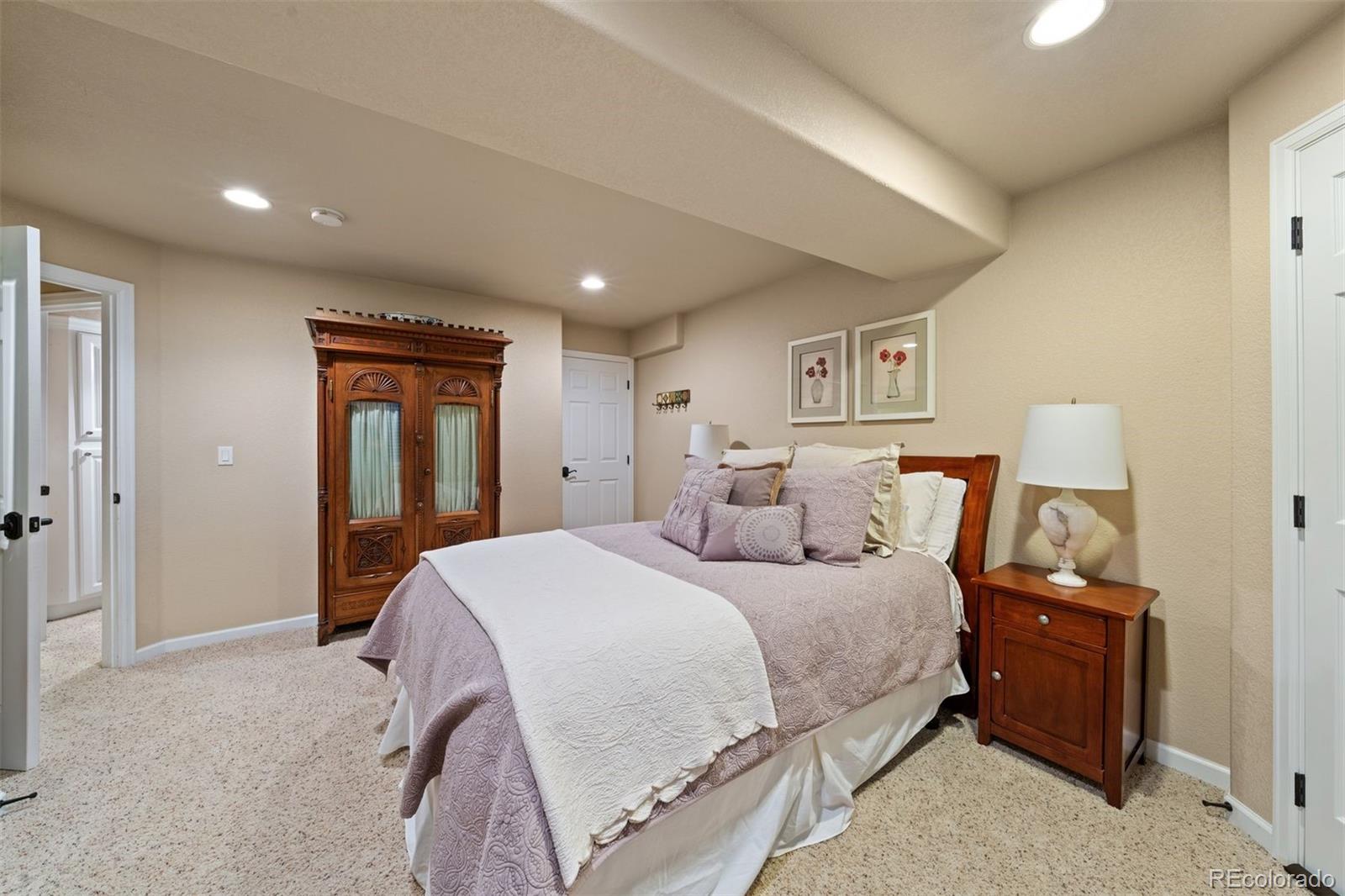10289 South Dan Court Highlands Ranch, CO 80130 - Photo 32 of 36 a spacious bedroom with a bed and a lamp