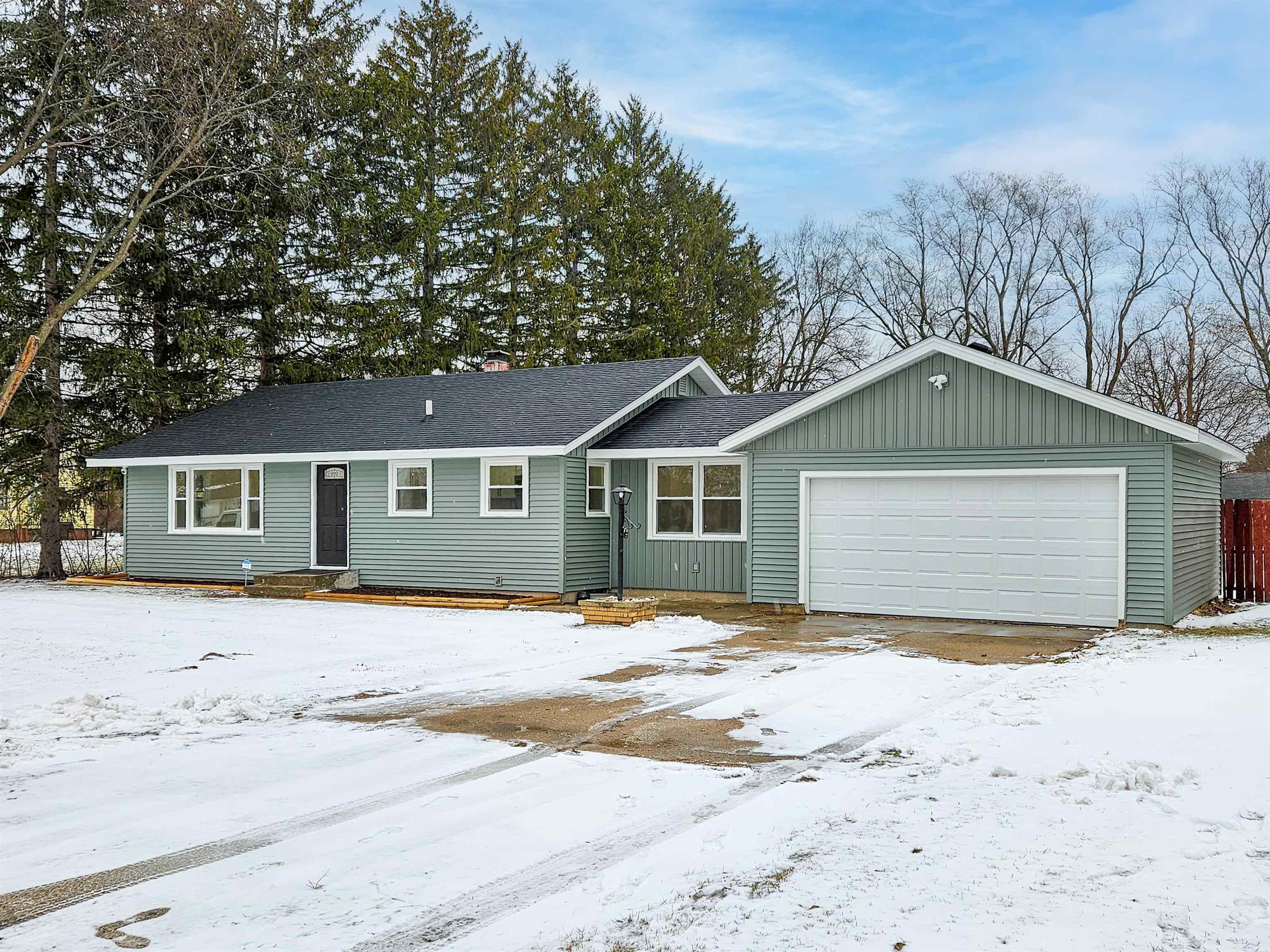 a front view of a house with a yard covered in snow