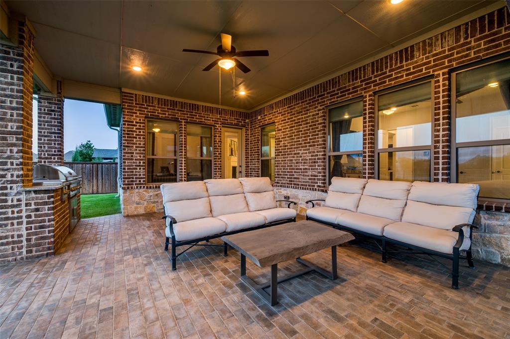 7821 Kentmere The Colony, TX 75056 - Photo 23 of 40 Enjoy year-round outdoor living on the expansive covered patio, complete with a cozy outdoor fireplace and ceiling fan for added comfort. This inviting space overlooks the oversized quarter-acre backyard and picturesque canal, creating the perfect setting for entertaining, relaxing, and taking in the peaceful water views.