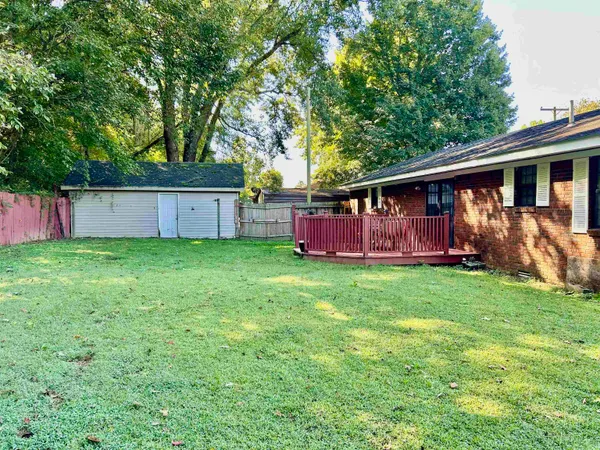 a view of backyard with large trees and wooden fence