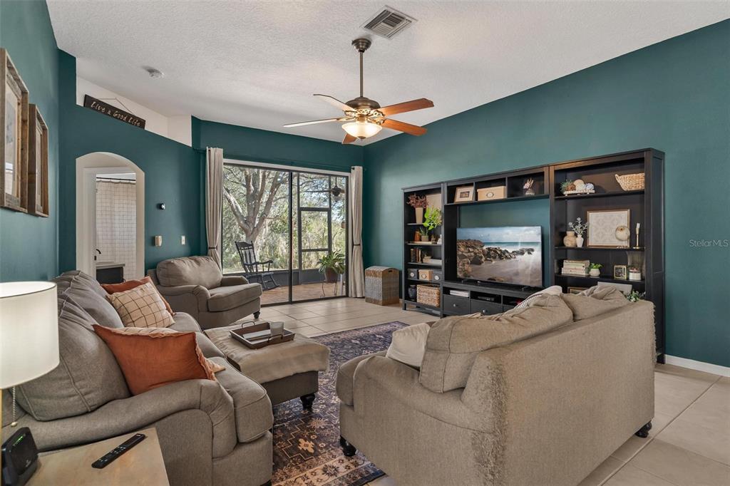 33142 Kaylee Way Leesburg, FL 34788 - Photo 12 of 45 a living room with furniture a ceiling fan and a flat screen tv