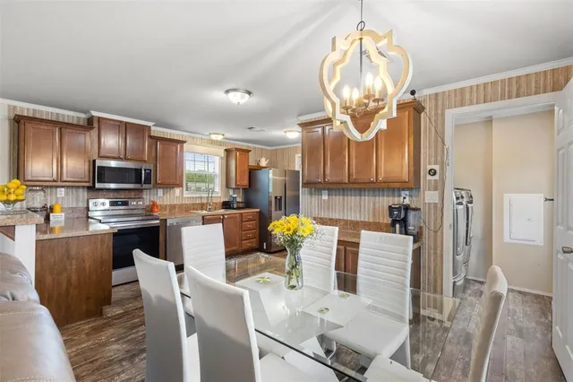 a kitchen with stainless steel appliances granite countertop a stove top oven a sink dishwasher a dining table and chairs with wooden floor