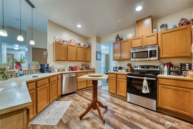 a kitchen with stainless steel appliances granite countertop a stove top oven a sink dishwasher a dining table and chairs with wooden floor