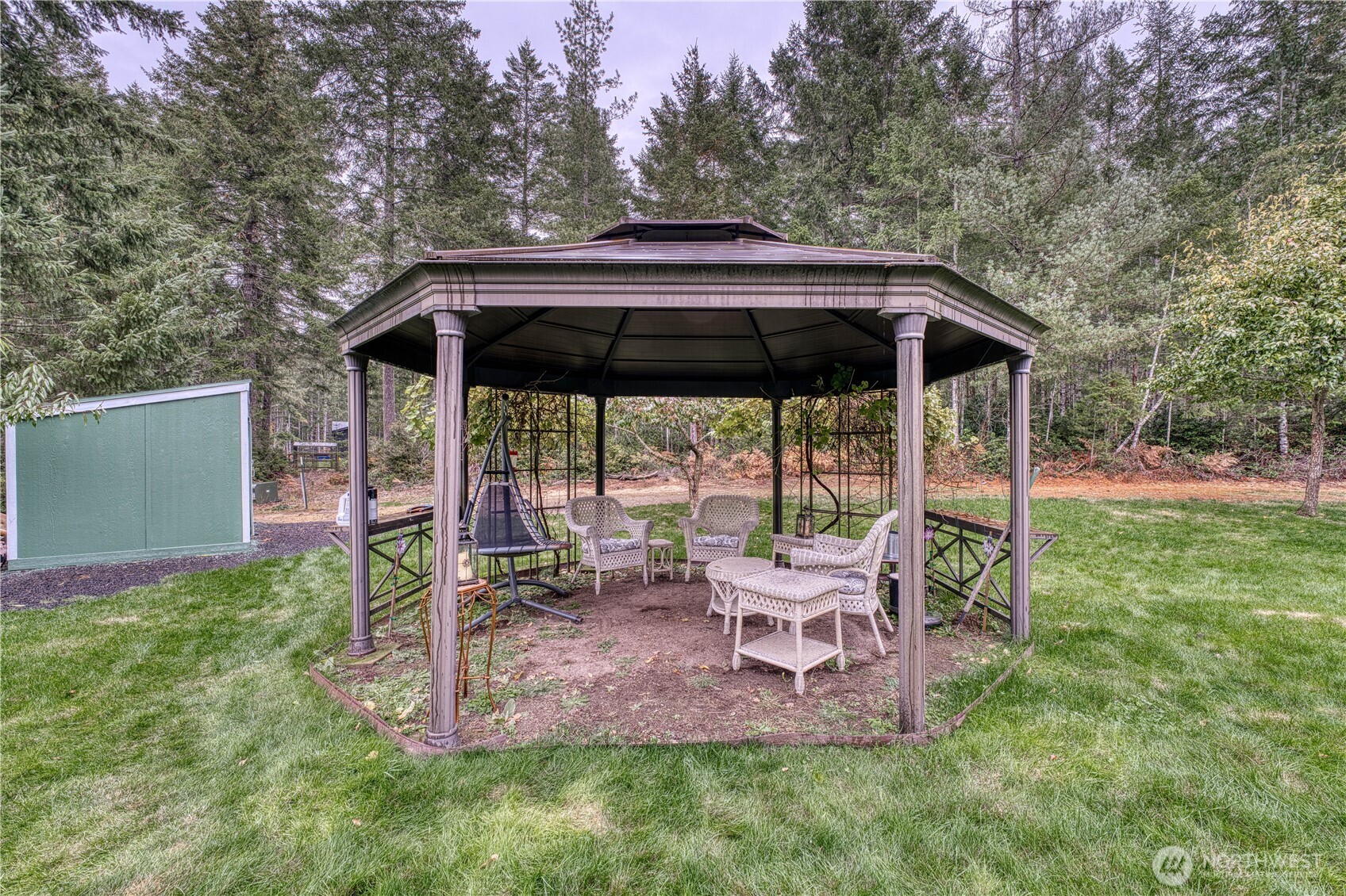991 Northeast Hurd Road Belfair, WA 98528 - Photo 9 of 40 a view of backyard with table and chairs under an umbrella with a barbeque