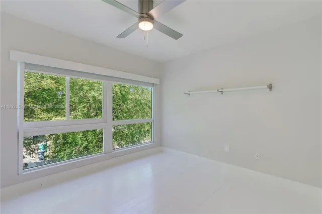 an empty room with windows and ceiling fan