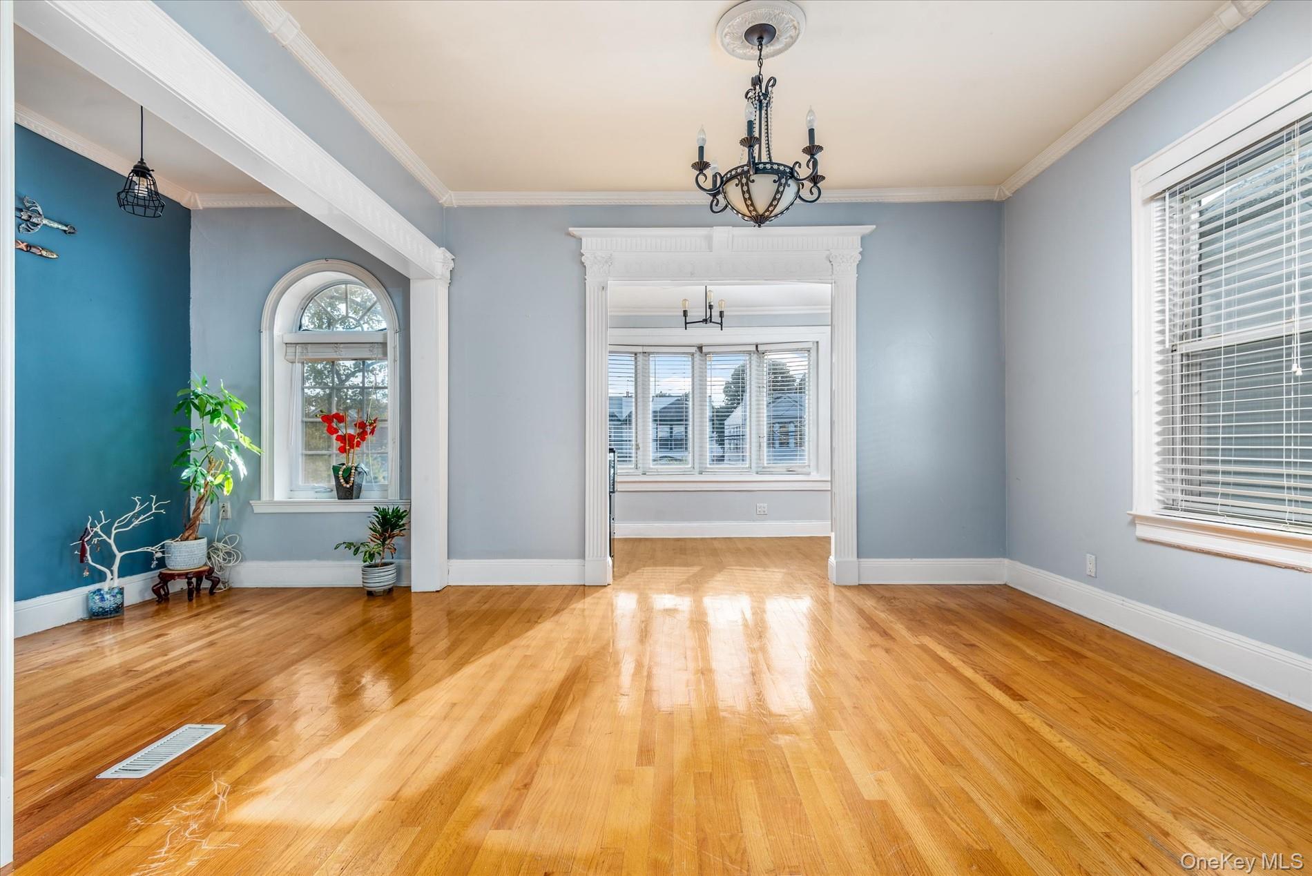93-17 123rd Street Queens, NY 11419 - Photo 11 of 40 Unfurnished dining area featuring plenty of natural light, a chandelier, wood finished floors, and crown molding