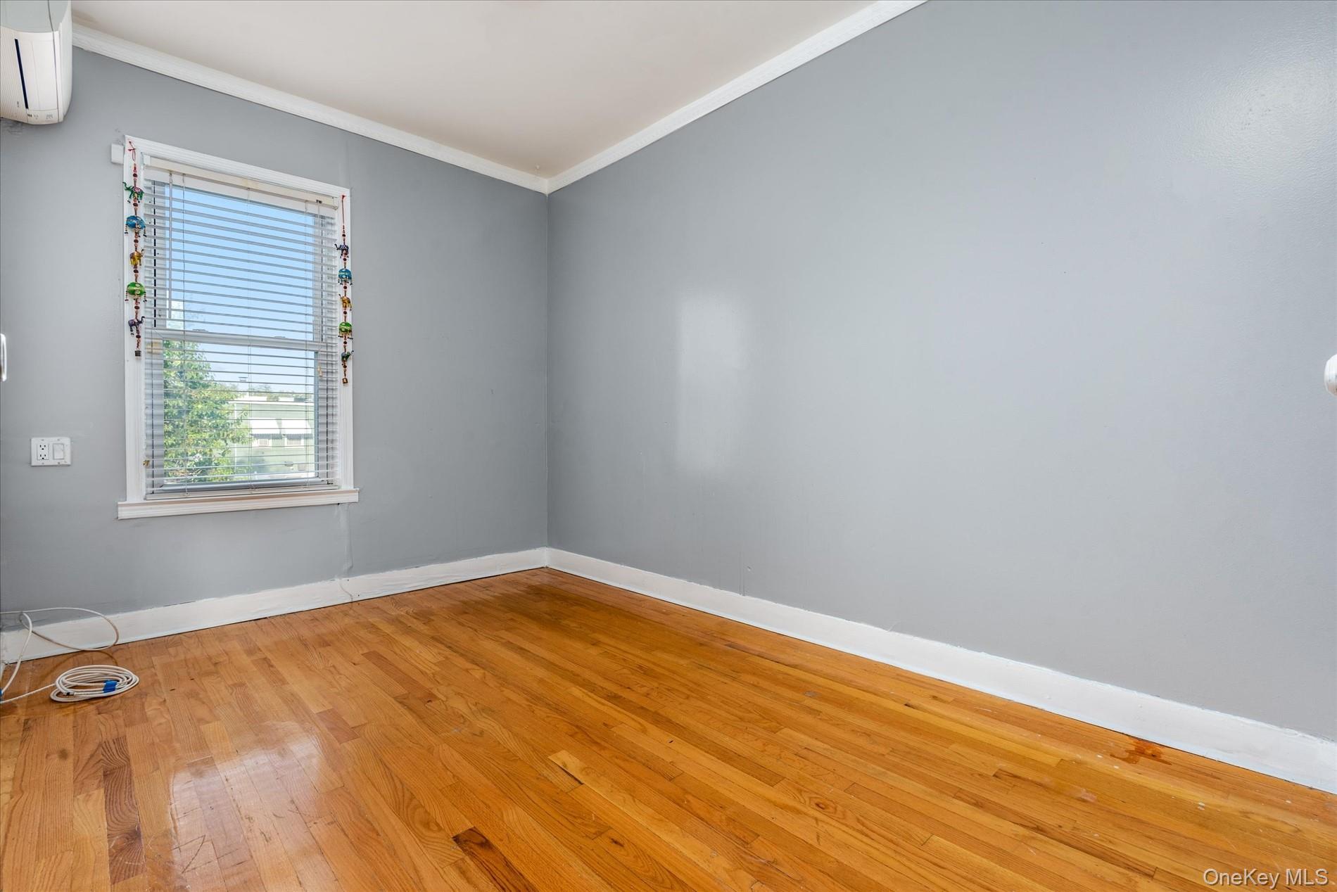 93-17 123rd Street Queens, NY 11419 - Photo 16 of 40 Spare room with wood-type flooring, an AC wall unit, and ornamental molding