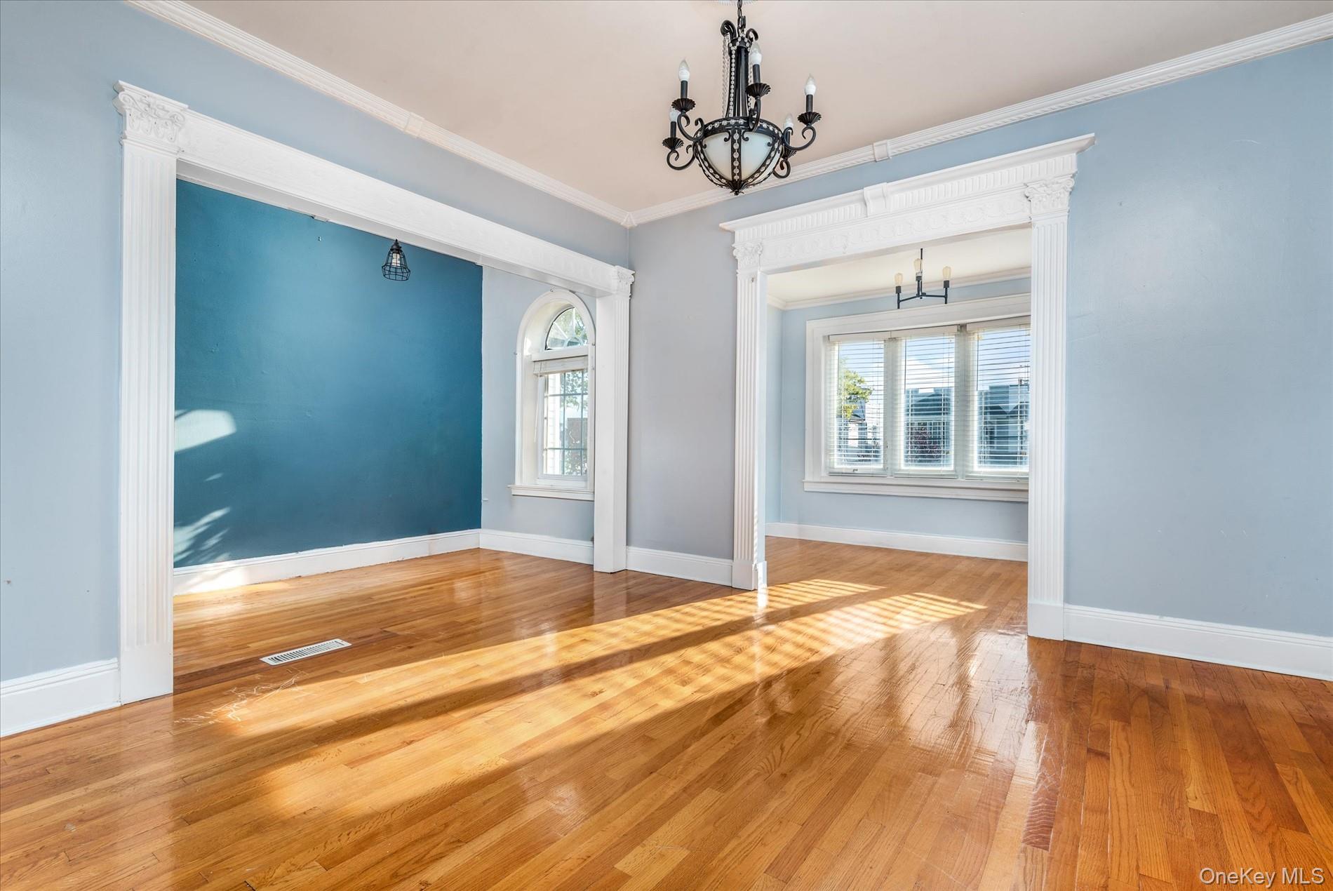 93-17 123rd Street Queens, NY 11419 - Photo 28 of 40 Unfurnished dining area with a chandelier, crown molding, hardwood / wood-style flooring, and ornate columns