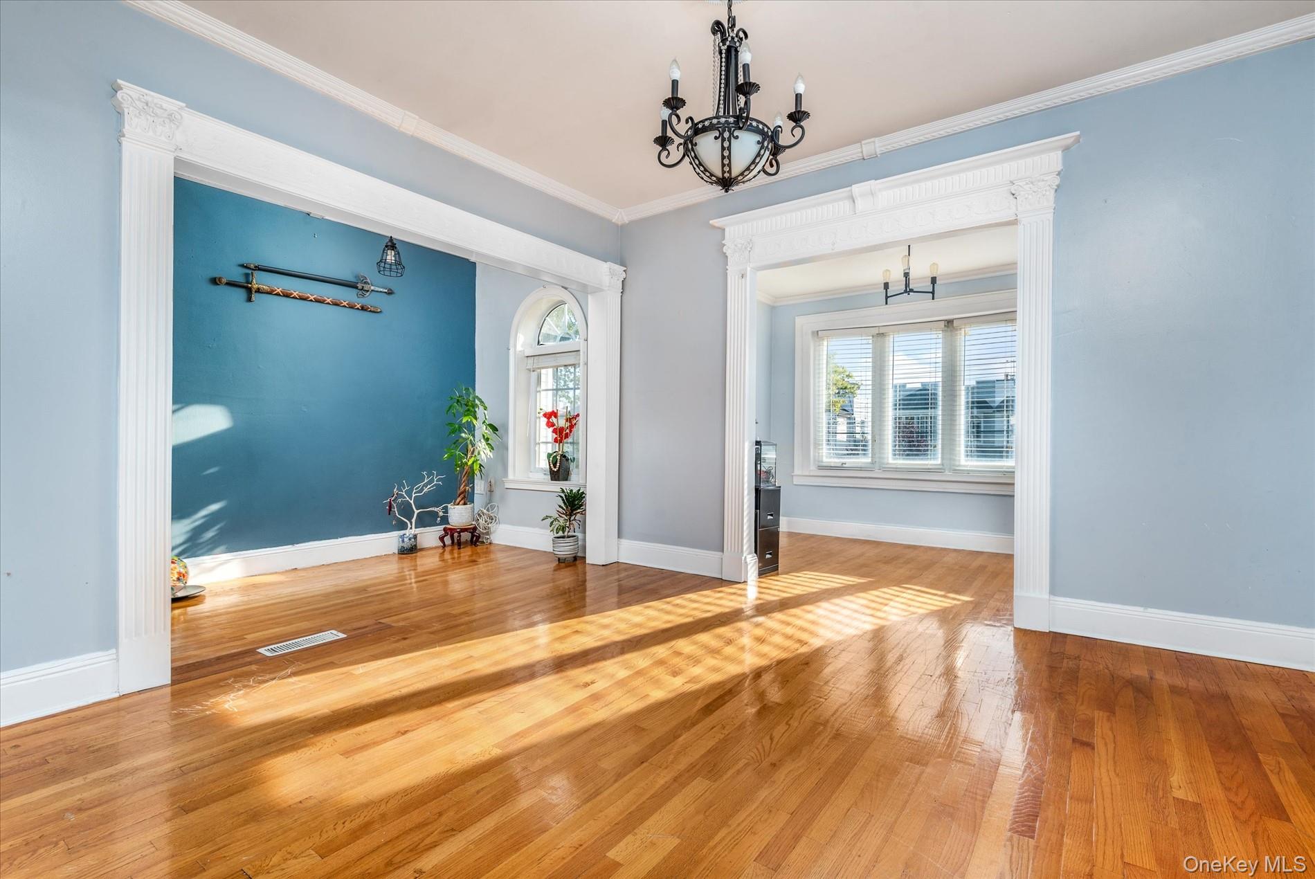 93-17 123rd Street Queens, NY 11419 - Photo 9 of 40 Unfurnished dining area with a chandelier, ornamental molding, hardwood / wood-style flooring, and decorative columns