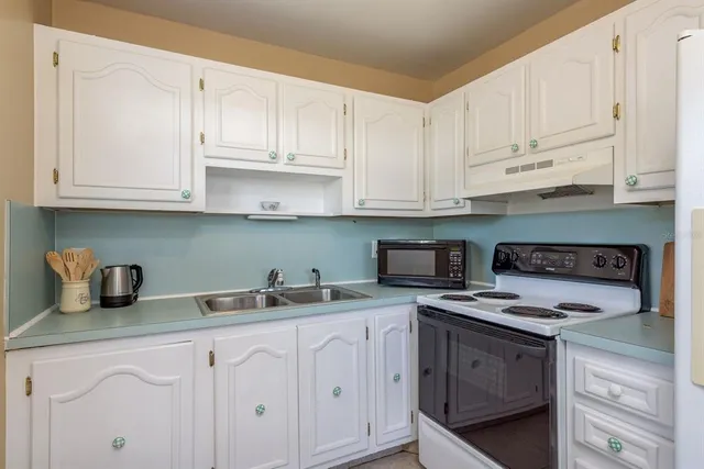a kitchen with white cabinets and white appliances