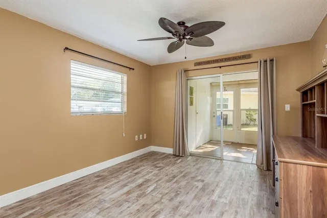 a view of empty room with wooden floor and fan