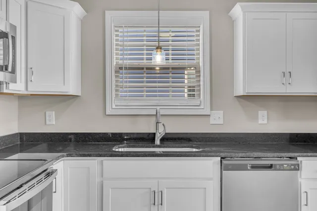 a kitchen with stainless steel appliances granite countertop white cabinets and a sink