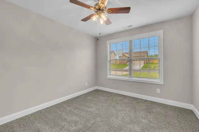 a view of an empty room with window and chandelier fan