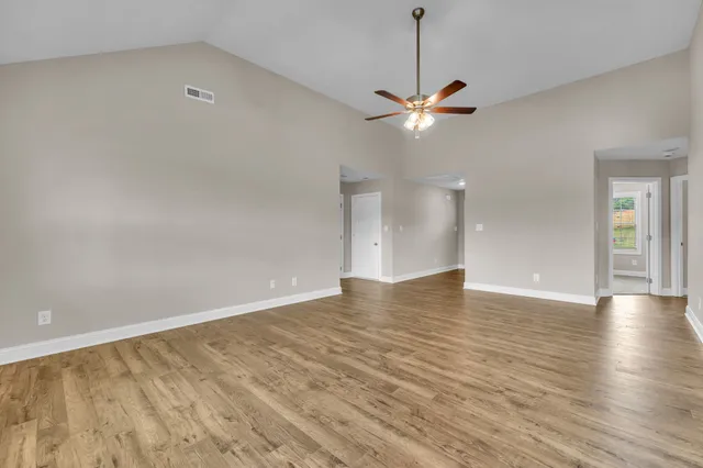 a view of an empty room with a ceiling fan and wooden floor