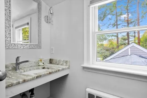 a bathroom with a granite countertop sink and a window
