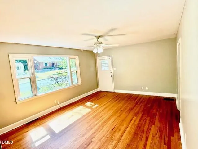 a view of an empty room with a window and wooden floor