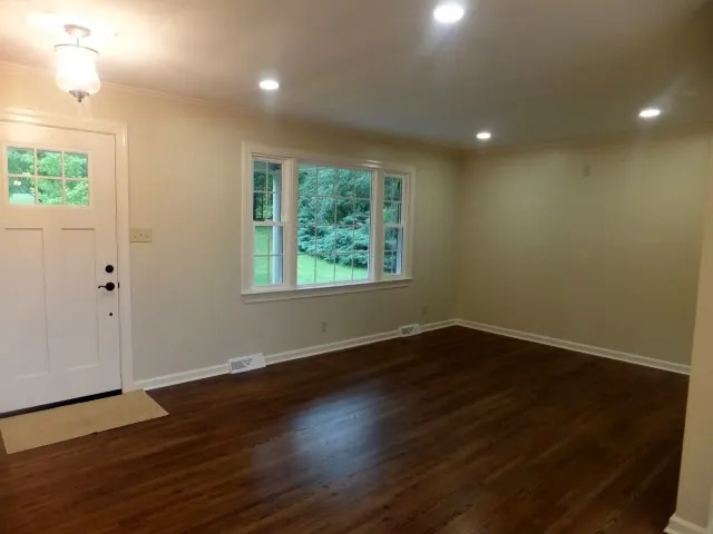 an empty room with wooden floor and windows
