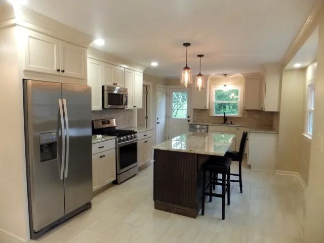 a kitchen with stainless steel appliances a refrigerator a stove a sink and chairs