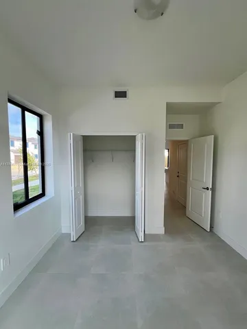 an empty room with a bathroom and windows