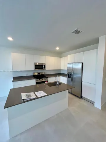 a kitchen with stainless steel appliances granite countertop a refrigerator a stove and a sink