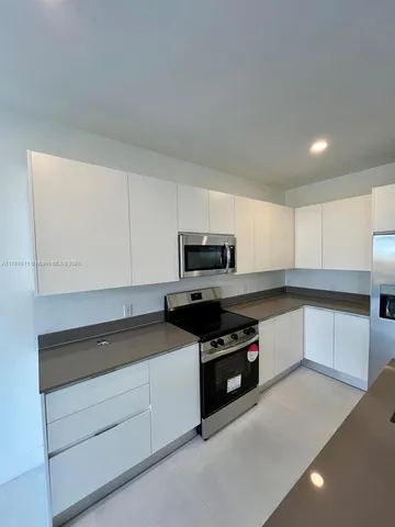 a kitchen with stainless steel appliances granite countertop a stove a sink and a microwave