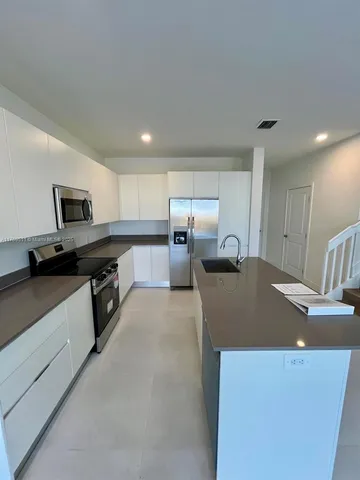 a kitchen with stainless steel appliances granite countertop a sink a stove and a refrigerator