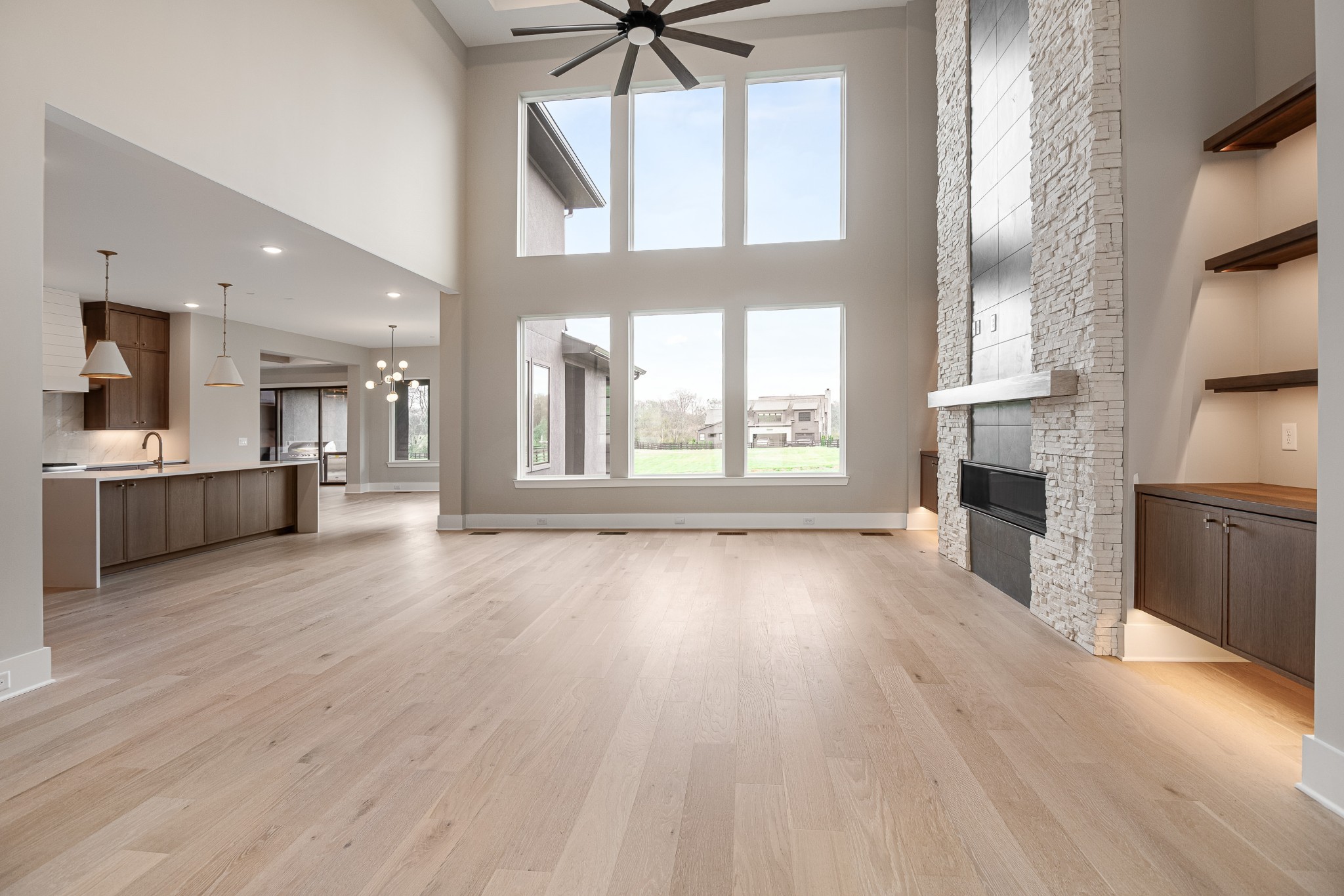 1764 Dean Road Thompson's Station, TN 37179 - Photo 11 of 45 an empty room with wooden floor a kitchen view and a fireplace