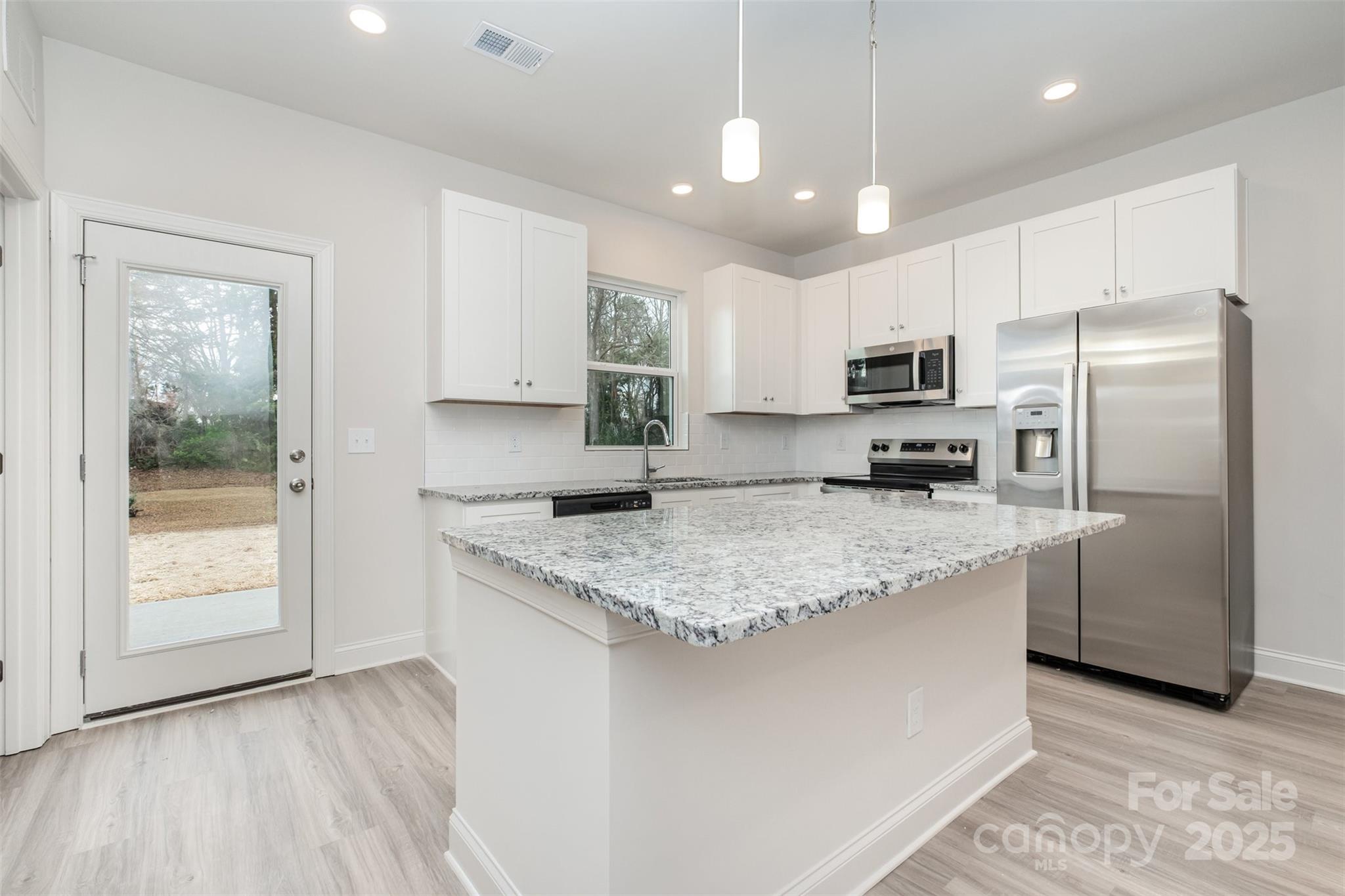 19901 Burton Lane Cornelius, NC 28031 - Photo 7 of 28 a kitchen with kitchen island granite countertop a stove a sink a refrigerator a center island and cabinets