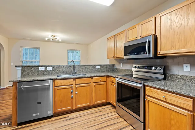 a kitchen with granite countertop cabinets stainless steel appliances a sink and a window