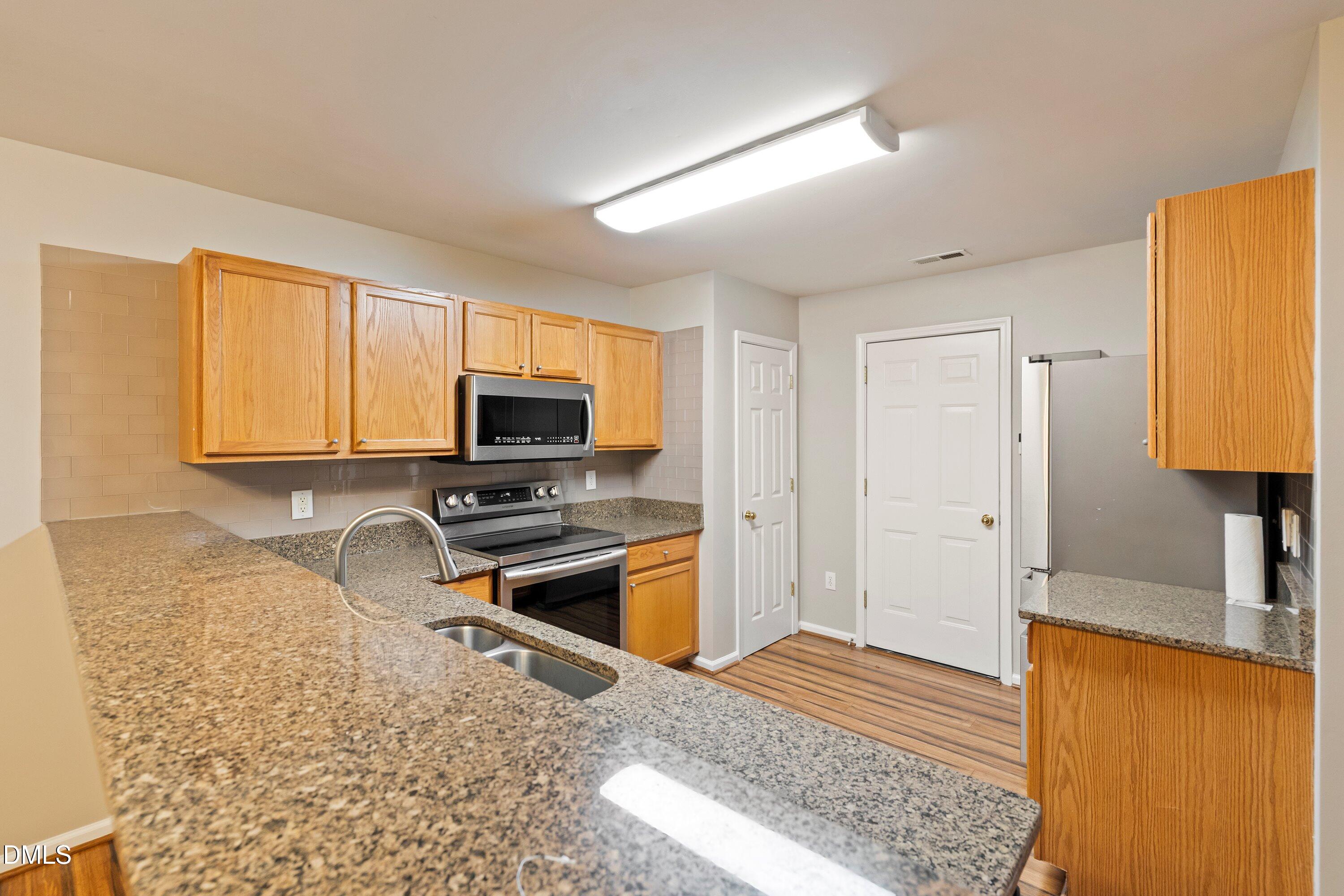 11 Kinglet Court Durham, NC 27713 - Photo 10 of 32 a kitchen with stainless steel appliances granite countertop a sink stove and refrigerator