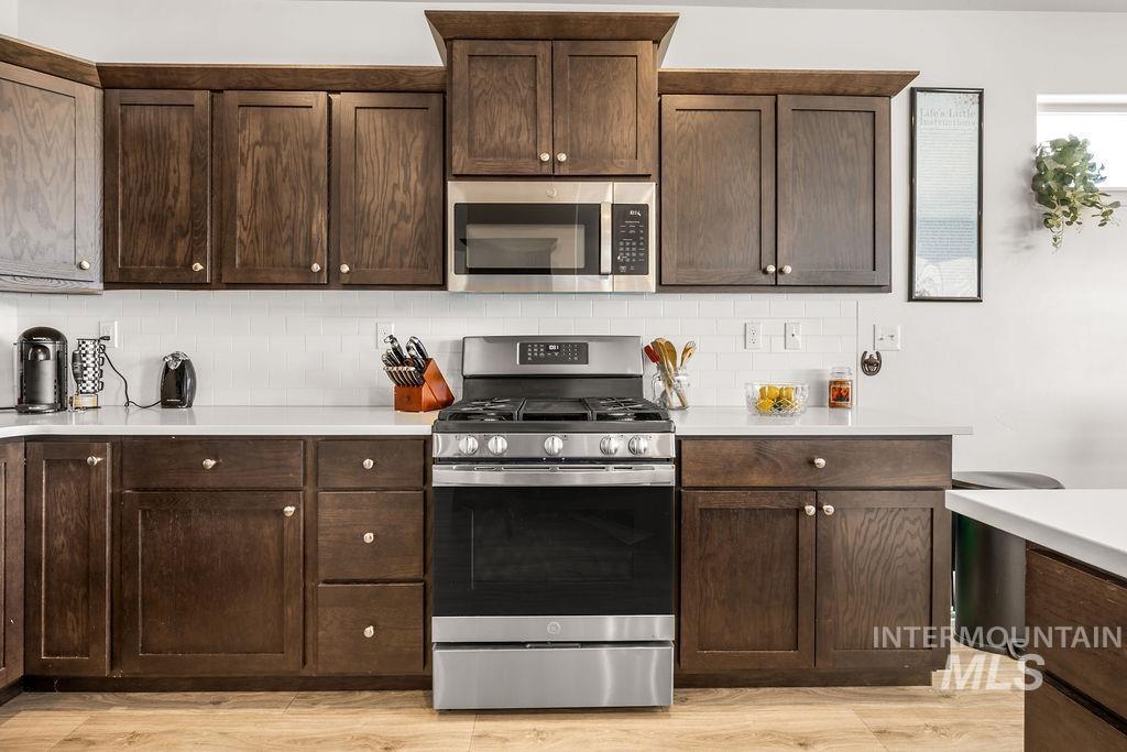 4601 Great Fls Avenue Caldwell, ID 83607 - Photo 11 of 29 Kitchen featuring dark wood-finish cabinetry, white subway tile backsplash, and light countertops
