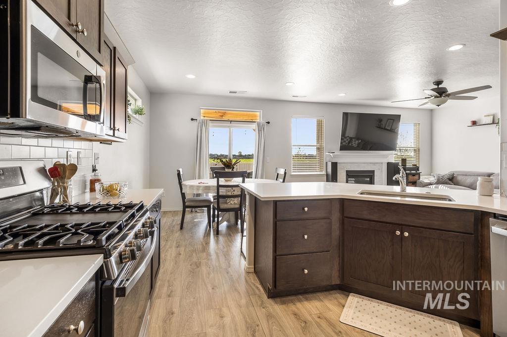 4601 Great Fls Avenue Caldwell, ID 83607 - Photo 12 of 29 Open-concept kitchen and living area featuring dark wood-finish cabinetry, light countertops, and a subway tile backsplash
