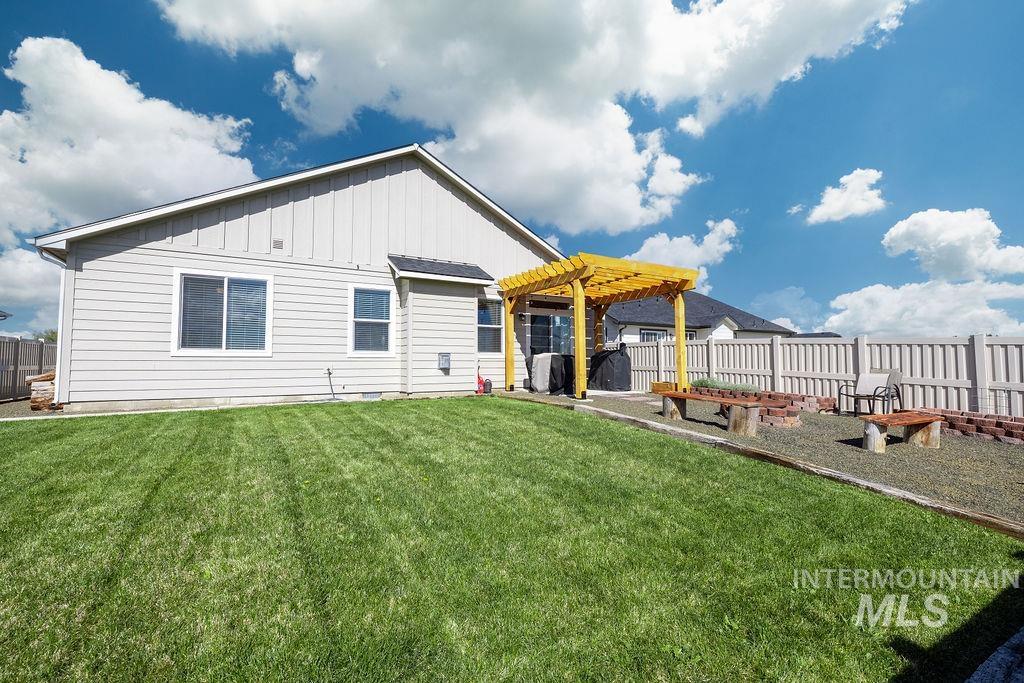 4601 Great Fls Avenue Caldwell, ID 83607 - Photo 28 of 29 Expansive backyard featuring a lush lawn, a pergola-covered patio, a gravel seating area with a brick-lined fire pit, and a solid privacy fence
