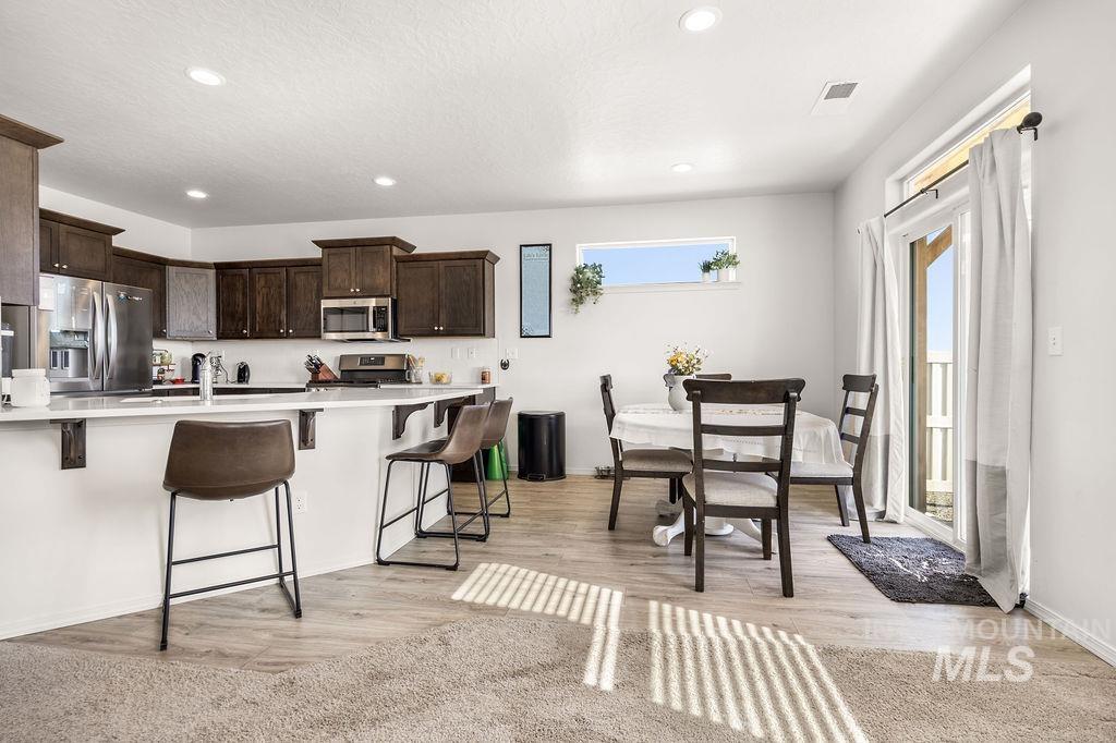 4601 Great Fls Avenue Caldwell, ID 83607 - Photo 8 of 29 Open-concept living space with a kitchen featuring dark wood cabinetry, stainless steel appliances, and a white countertop island with seating