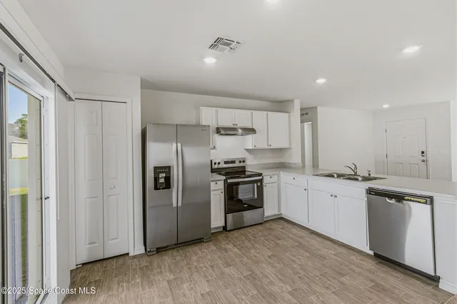 a kitchen with granite countertop a refrigerator stove top oven and sink