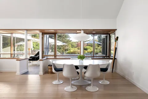 a dining room with wooden floor and large windows