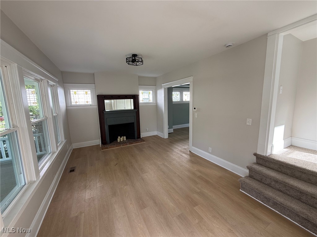2185 Rexwood Road Cleveland, OH 44118 - Photo 2 of 26 Unfurnished living room featuring healthy amount of natural light, light wood-style floors, and a fireplace with raised hearth