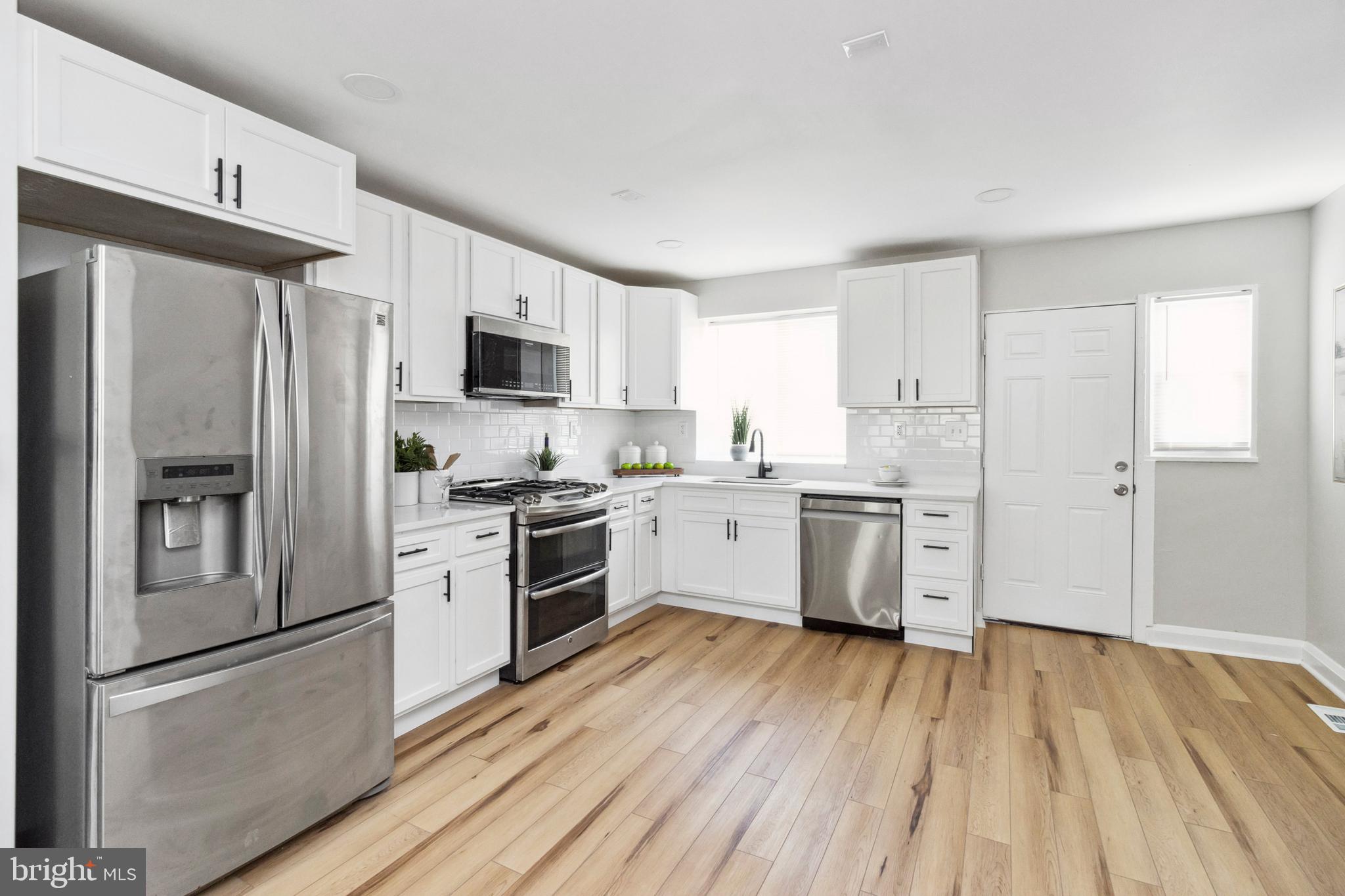 a kitchen with a refrigerator a stove top oven and white cabinets