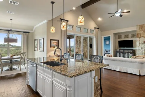 a large kitchen with granite countertop a large stove a sink dishwasher a dining table and chairs with wooden floor