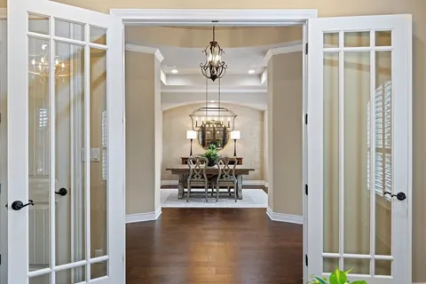 a living room with chandelier and wooden floor