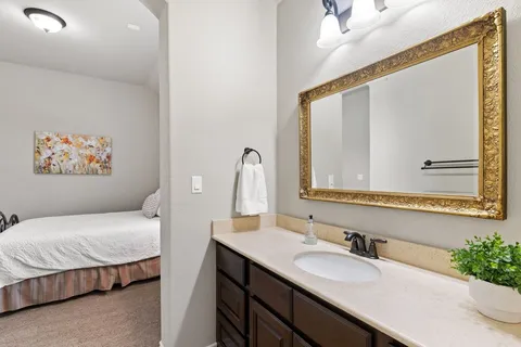 a en suite bathroom with a granite countertop sink and a mirror